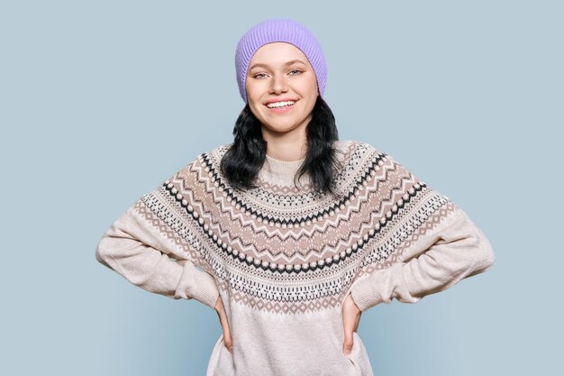 Portrait of young woman in knitted hat in woolen sweater on light gray color studio background Winter season Christmas and New Year holidays fashion beauty concept