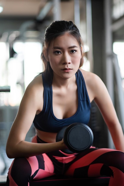 Portrait of young woman lifting dumbbell at gym