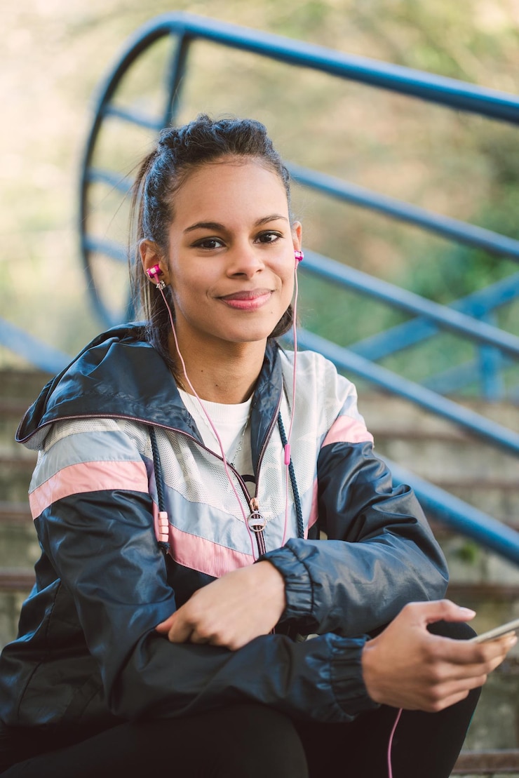 Photo portrait of young woman listening music through mobile phone on stairs