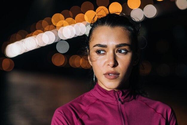 Photo portrait of young woman looking away at night