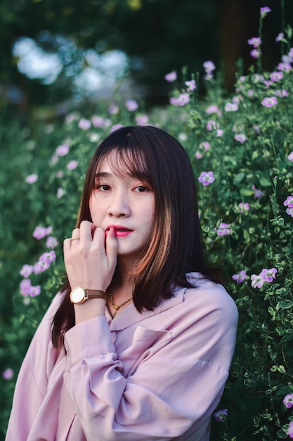 Portrait of young woman looking away while standing against plants