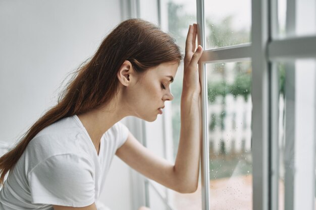 Photo portrait of young woman looking away while standing against window