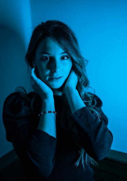 Портрет молодой женщины, смотрящей в камеру с синими светодиодными огнями сбоку