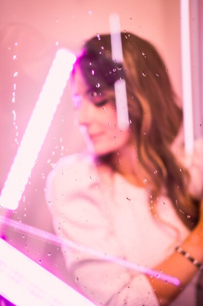 Portrait of a young woman looking at camera with pink led lights from one side