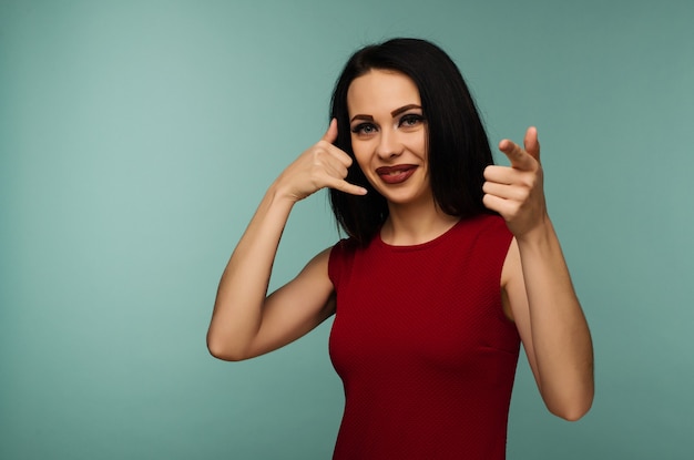 Portrait of an young woman looking and pointing at you saying call me on isolated