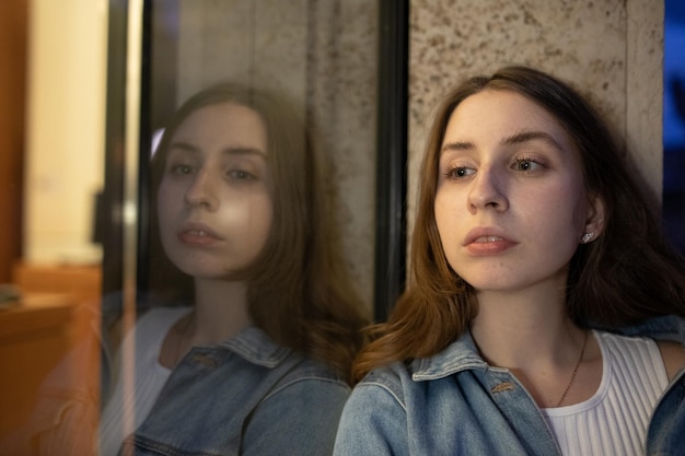 Photo portrait of young woman looking through window