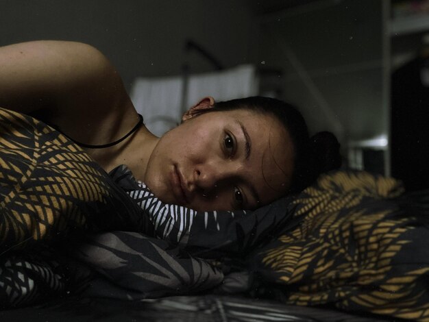 Photo portrait of young woman lying on bed at home