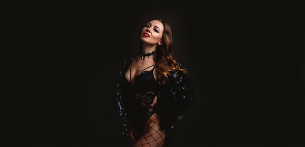 portrait young woman middle old aged model in stage black costume dress posing on black background. face of pretty female with fashion makeup and long hair. wallpaper for ad. concept beauty and health