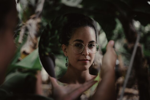 Foto ritratto di una giovane donna nello specchio con gli occhiali