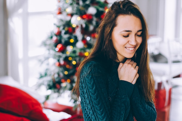 Portrait of a young woman at the New Year tree. A woman makes a wish by the New Year tree.