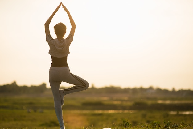 Portrait of a Young Woman performing Yoga outside in sunny bright light.