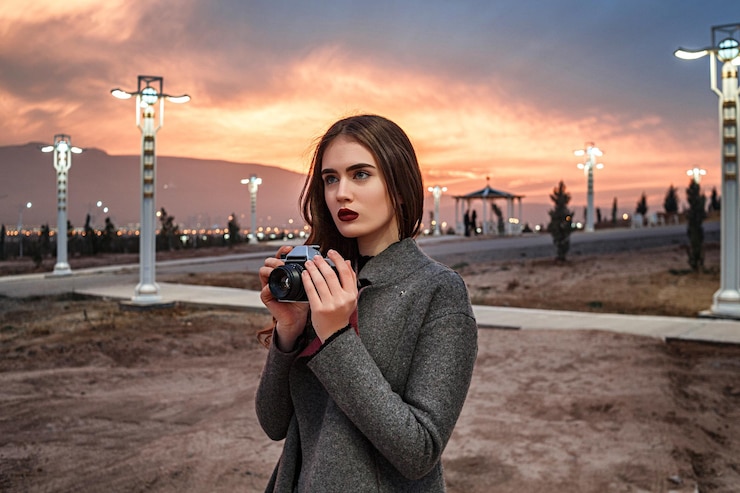 Photo portrait of young woman photographing against sky during sunset