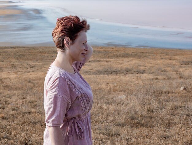 Photo portrait of a young woman in a pink dress in the fields