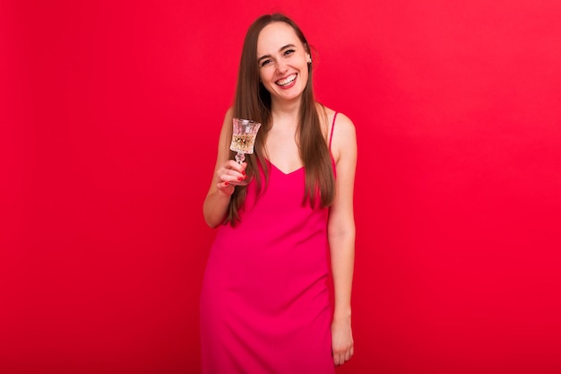 Portrait of a young woman in a pink dress with a glass of champagne Beautiful evening dress for the holiday