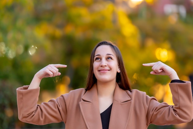 Portrait of a young woman pointing at herself