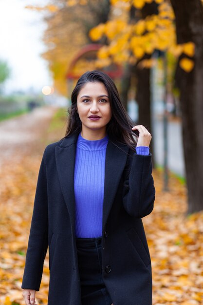 Portrait of a young woman posing in autumn park