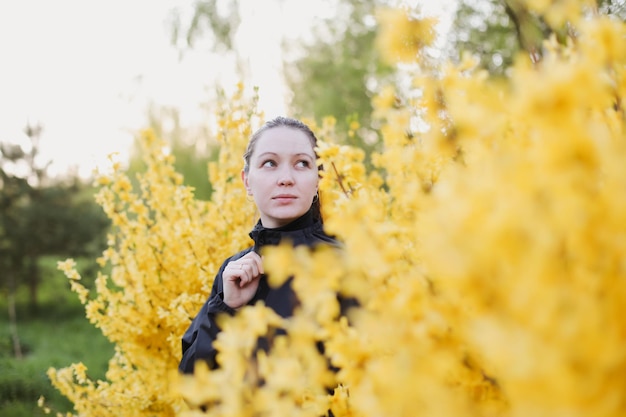 Portrait of young woman posing in blooming spring garden Girl surrounded with flowers