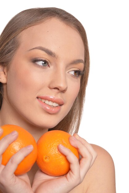 Portrait of young woman posing with oranges on white background