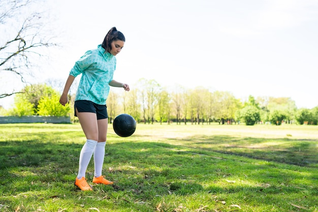 Portrait of young woman practicing soccer skills and doing tricks with the football ball. Soccer player juggling the ball.