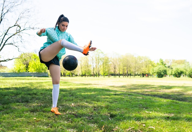 Photo portrait of young woman practicing soccer skills and doing tricks with the football ball.