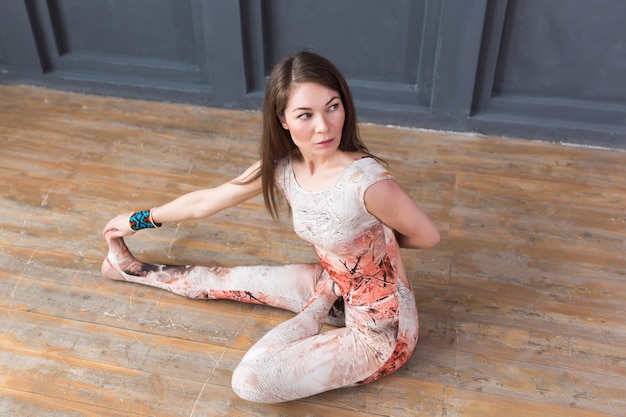 Photo portrait of young woman practicing yoga indoor on urban grey wall