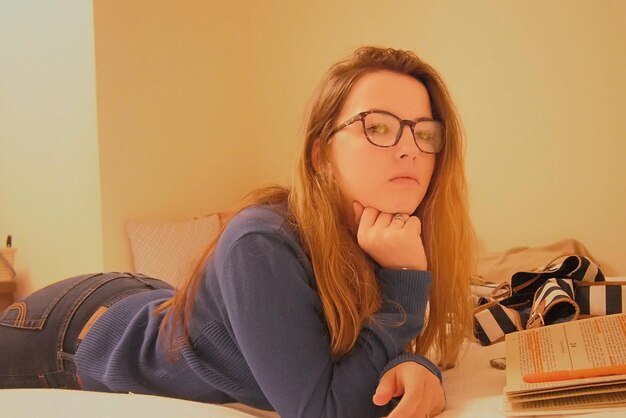 Photo portrait of young woman reading book while lying on bed