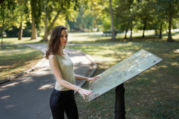 Foto ritratto di una giovane donna che legge una mappa in piedi al parco