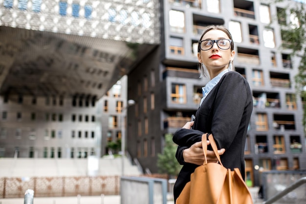 Portrait of a young woman realtor or businesswoman standing outdoors on the modern residential district background