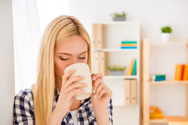 Ritratto di giovane donna che riposa e che beve caffè in ufficio