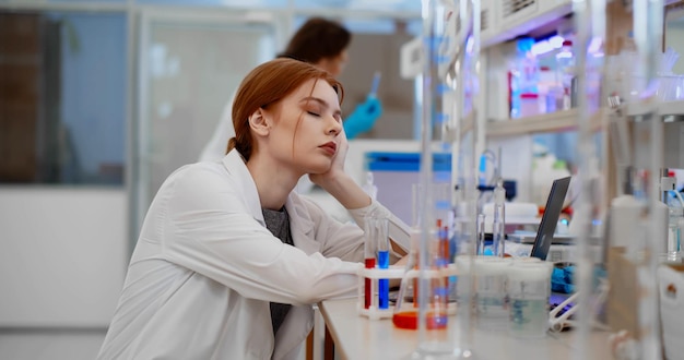 Photo portrait young woman scientist sleeping feeling tired working in medical laboratory