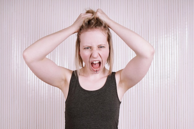 Photo portrait of young woman screaming against blinds