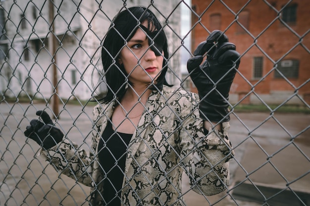 Photo portrait of young woman seen through chainlink fence