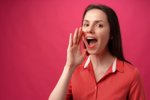 Portrait of young woman shouting over pink background