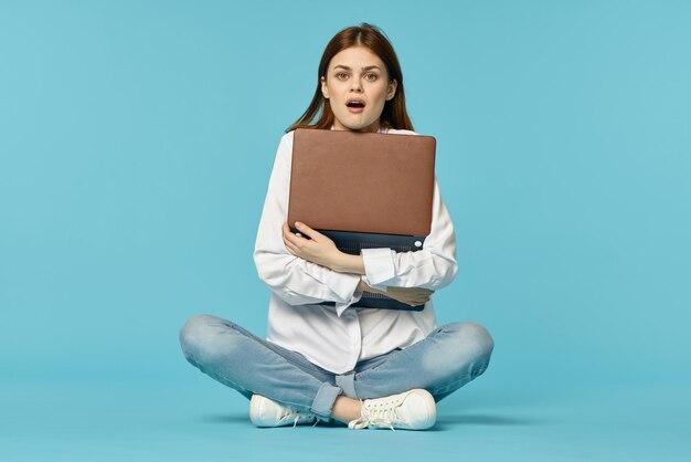 Portrait of young woman sitting against blue background