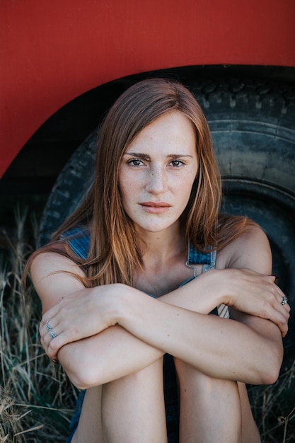 Photo portrait of young woman sitting against tire