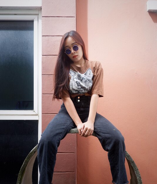 Photo portrait of young woman sitting against wall