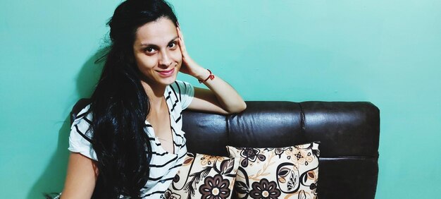 Portrait of young woman sitting against wall