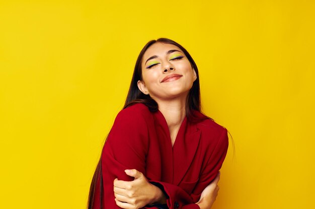 Portrait of young woman sitting against yellow background