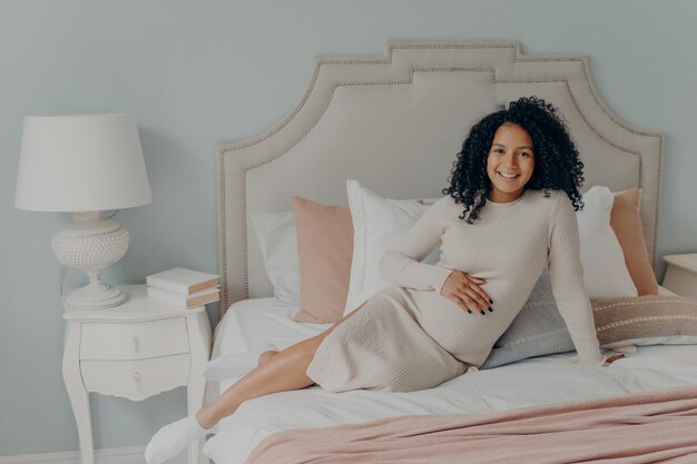 Photo portrait of young woman sitting on bed at home