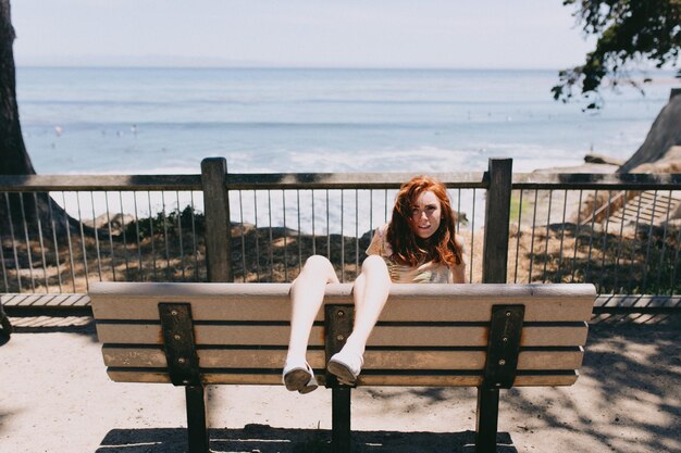 Photo portrait of young woman sitting on bench by sea