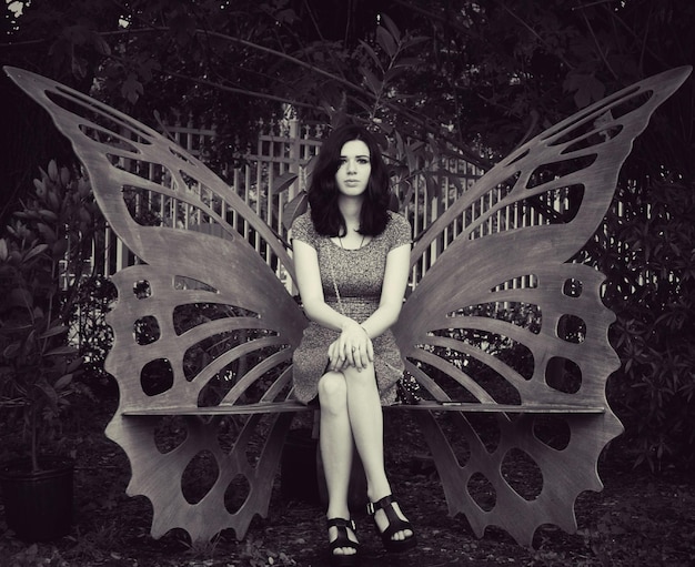 portrait of young woman sitting on butterfly bench