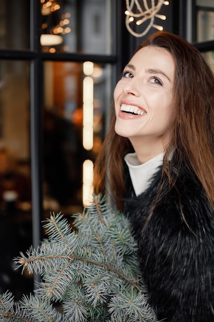 Portrait of young woman sitting in cafe in winter town and posing for a photo