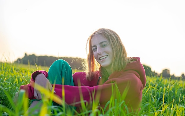 Foto ritratto di una giovane donna seduta sul campo contro un cielo limpido