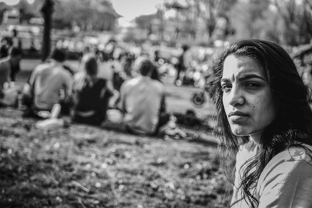 Foto ritratto di una giovane donna seduta sul campo al parco