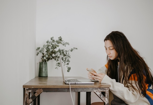 Portrait of young woman sitting at home with mobile phone