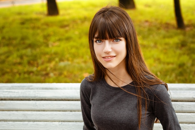 Portrait of a young woman sitting in the park on a bench