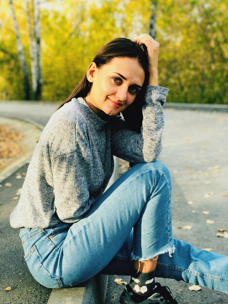 Portrait of young woman sitting on road