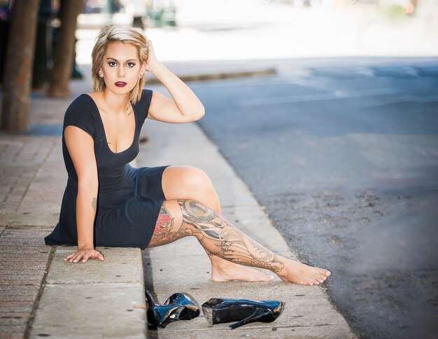 Portrait of young woman sitting on sidewalk