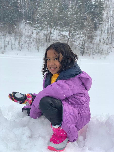 Photo portrait of young woman sitting on snow covered field