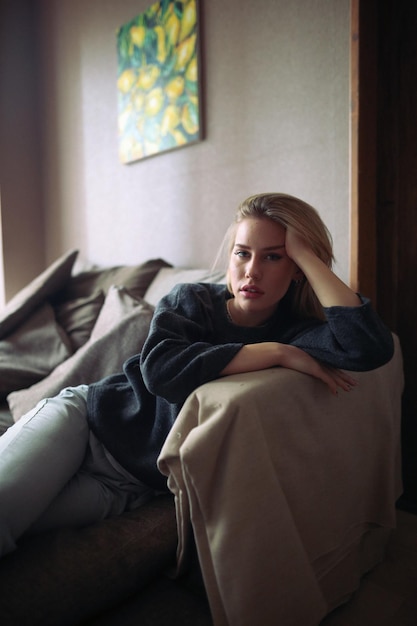 portrait of young woman sitting on sofa at home